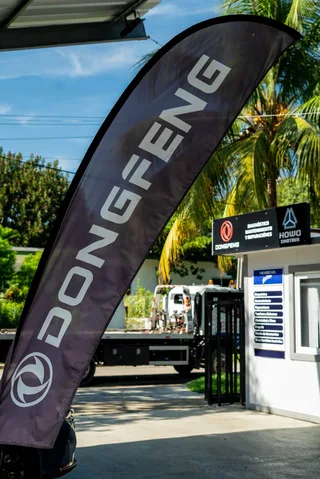Bandera de Dongfeng frente a un área de diagnóstico y mantenimiento, con un camión de plataforma al fondo en La Habana.