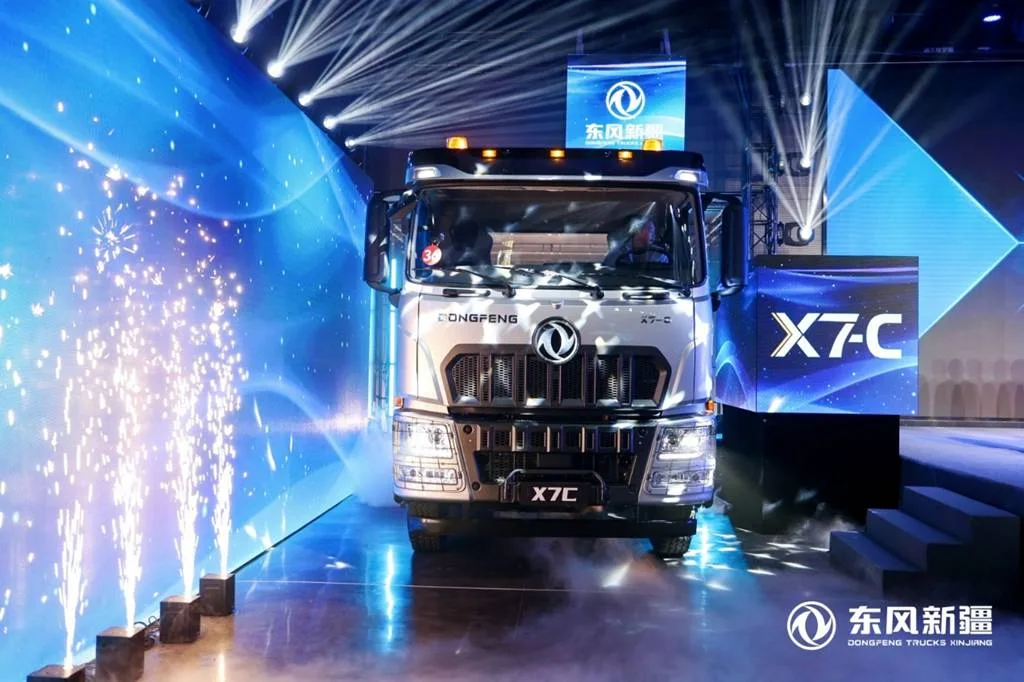 Camión Dongfeng Changxing X7-C plateado visto de frente en un escenario de presentación con iluminación azul y el nombre X7-C al fondo.