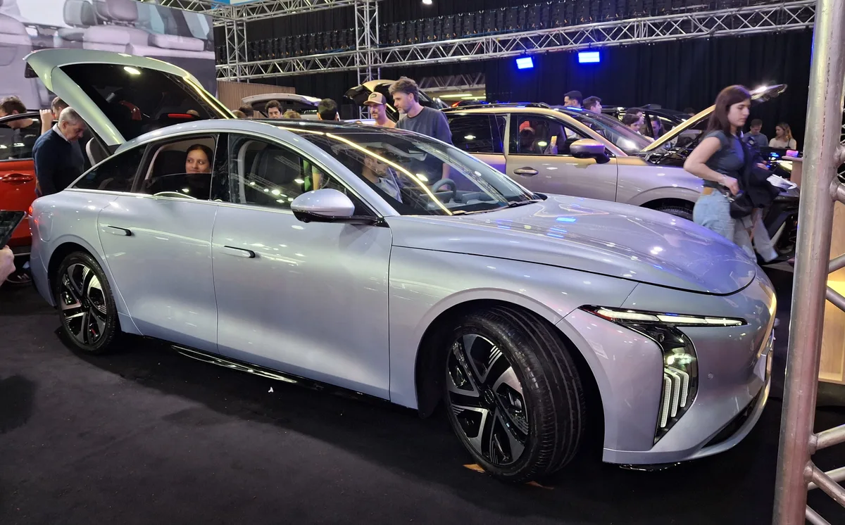 Sedán FORTHING S7 REEV de color gris azulado expuesto en Expo Auto Chino 2026, en Buenos Aires, con visitantes a su alrededor.