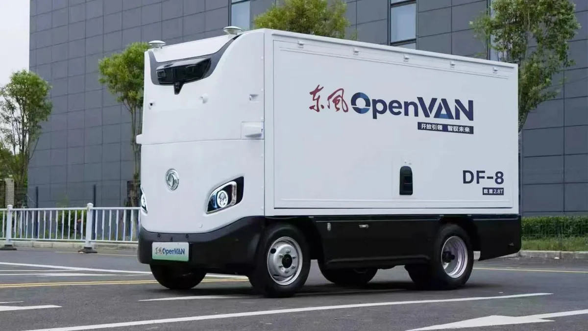 Vehículo de reparto autónomo Dongfeng OpenVAN DF-8 blanco, con carrocería de caja cerrada, fotografiado en una calle frente a un edificio.