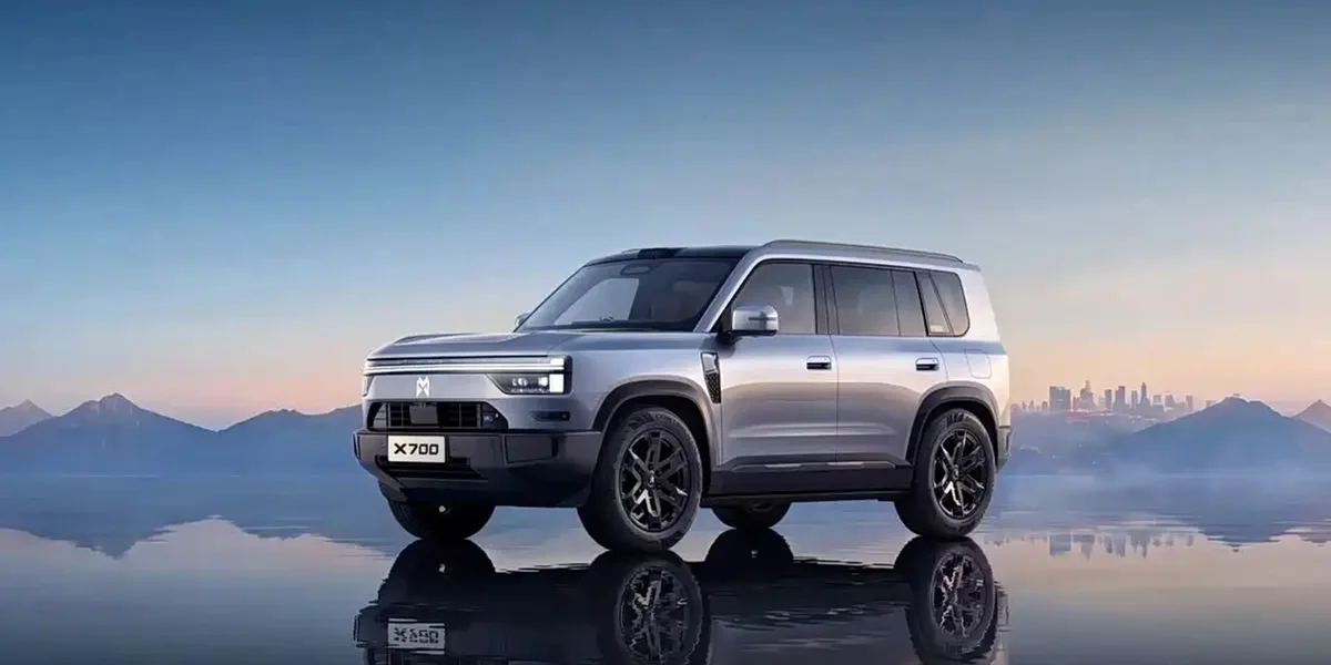 SUV Dongfeng Mengshi X700 plateado, visto en perspectiva frontal y lateral sobre una superficie reflectante, con montañas al fondo.
