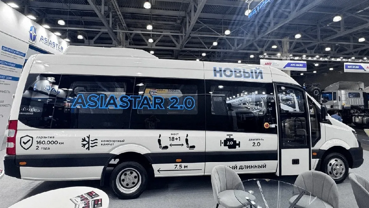 Minibús blanco Asiastar Eurise 2.0 expuesto en un pabellón ferial, visto de perfil con la puerta abierta y rotulación del modelo en ruso sobre las ventanas.