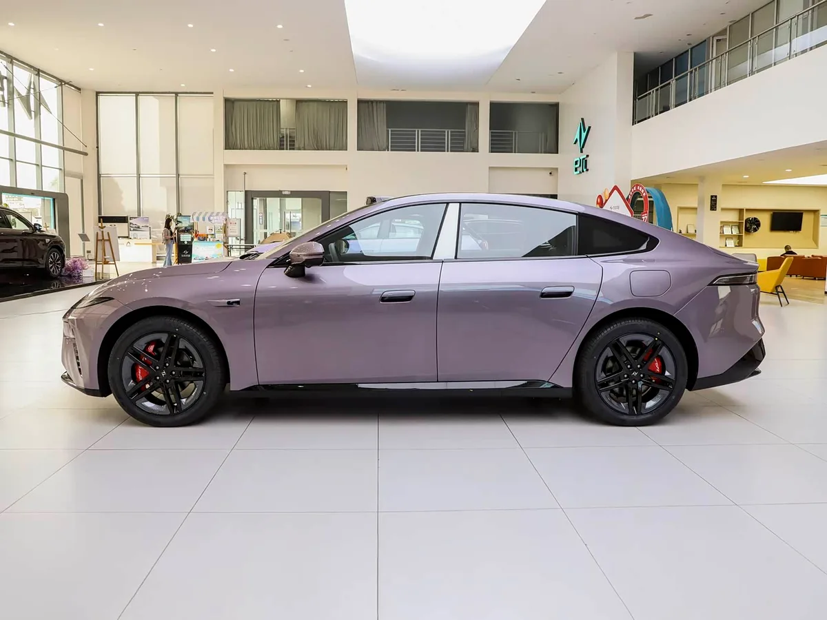Dongfeng eπ007 violeta visto de perfil dentro de un concesionario, con llantas negras y silueta de estilo coupé.
