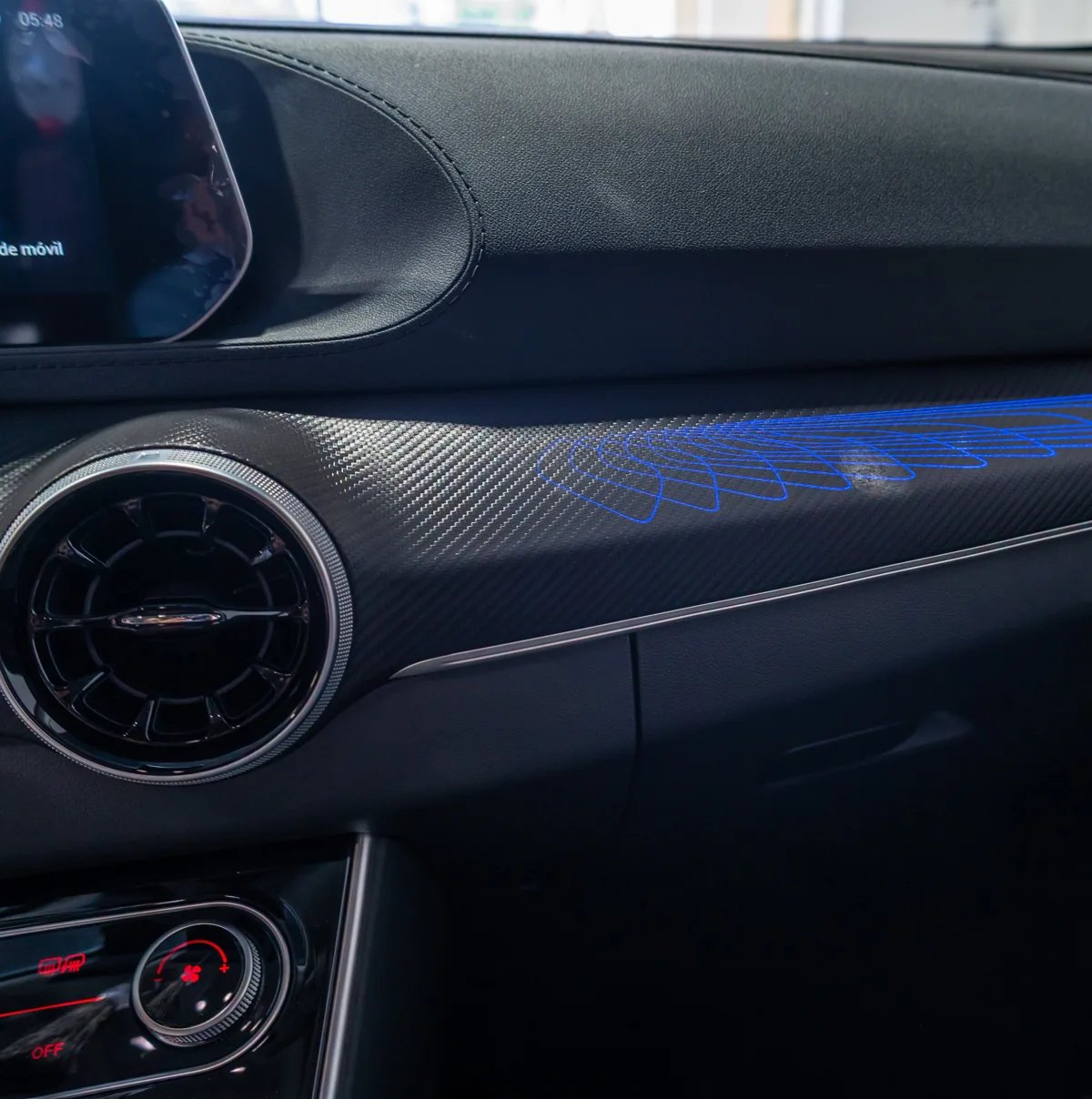 Detalle del salpicadero del Dongfeng Forthing T5 EVO con salida de aire circular, acabado texturizado e iluminación azul.