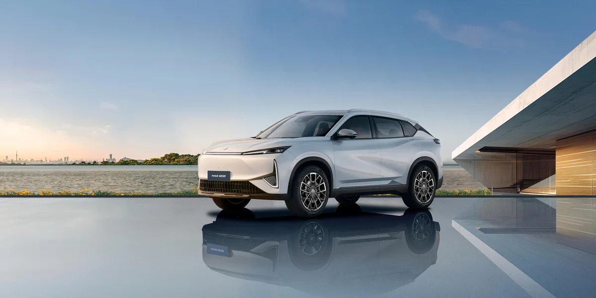 SUV eléctrico Dongfeng Mage EV blanco, visto de frente y de lado junto a una edificación moderna y un lago, con su reflejo sobre el suelo pulido.