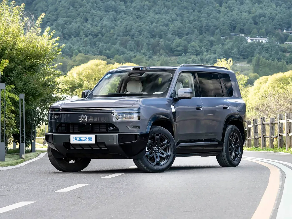Dongfeng Mengshi X700 gris visto de tres cuartos delanteros sobre una carretera, con montañas y vegetación al fondo.