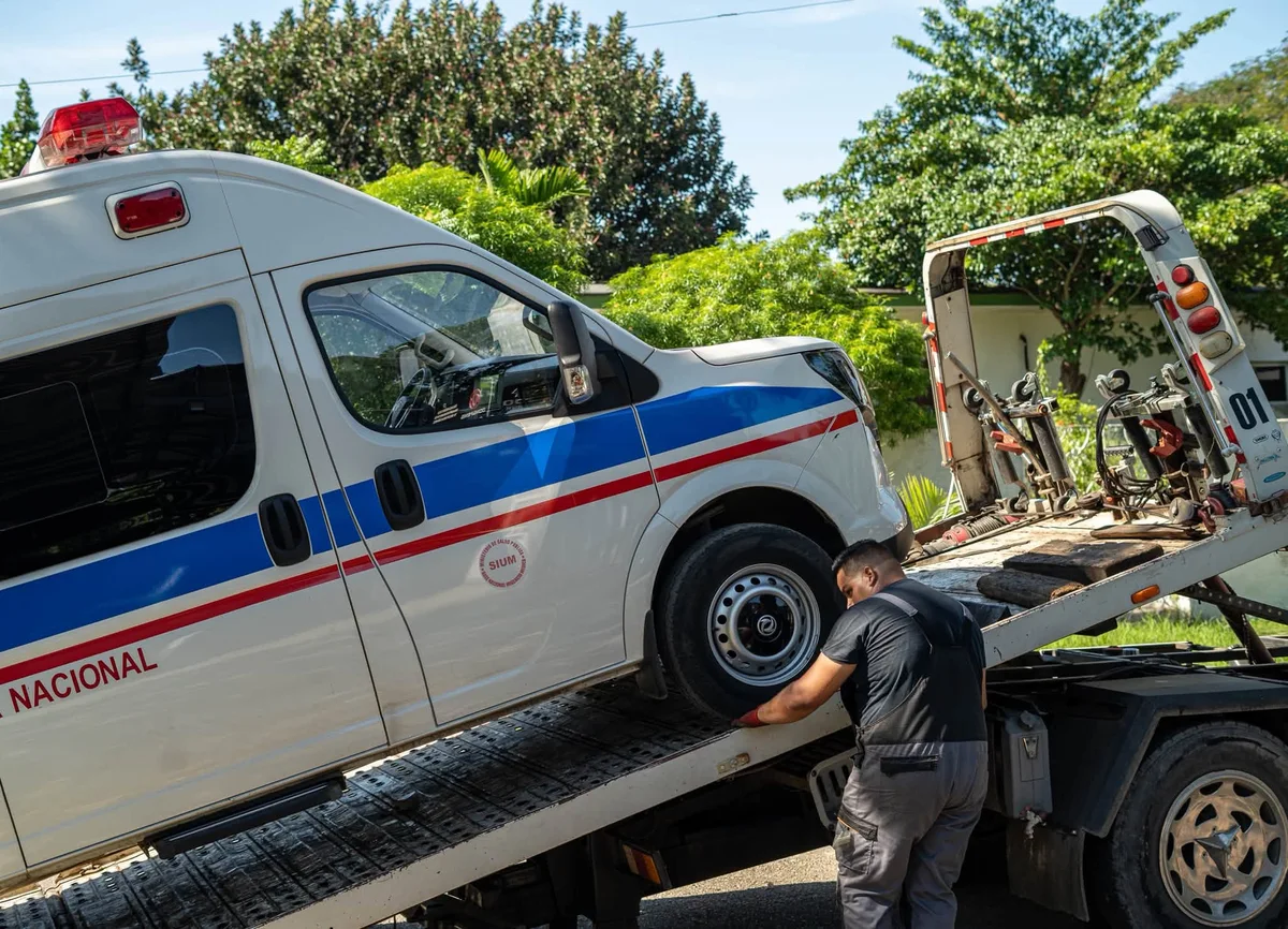 Operario junto a una ambulancia durante su carga en una grúa de plataforma en La Habana.