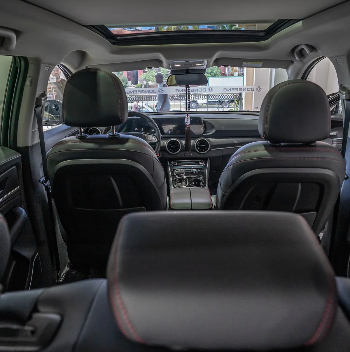 Habitáculo del Dongfeng Forthing T5 EVO visto desde la parte trasera, con asientos delanteros, tablero y techo panorámico.