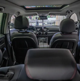Habitáculo del Dongfeng Forthing T5 EVO visto desde la parte trasera, con asientos delanteros, tablero y techo panorámico.