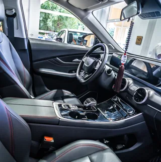 Interior del Dongfeng Forthing T5 EVO con volante, pantallas digitales, asientos delanteros y consola central.