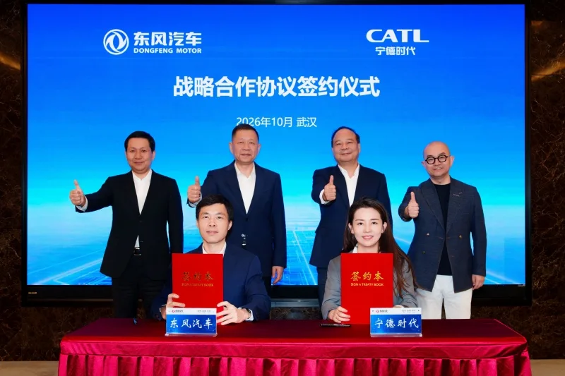 Dos representantes de Dongfeng Motor y CATL muestran carpetas rojas durante la firma de un acuerdo, ante cuatro directivos y una pantalla con los logotipos de ambas empresas.