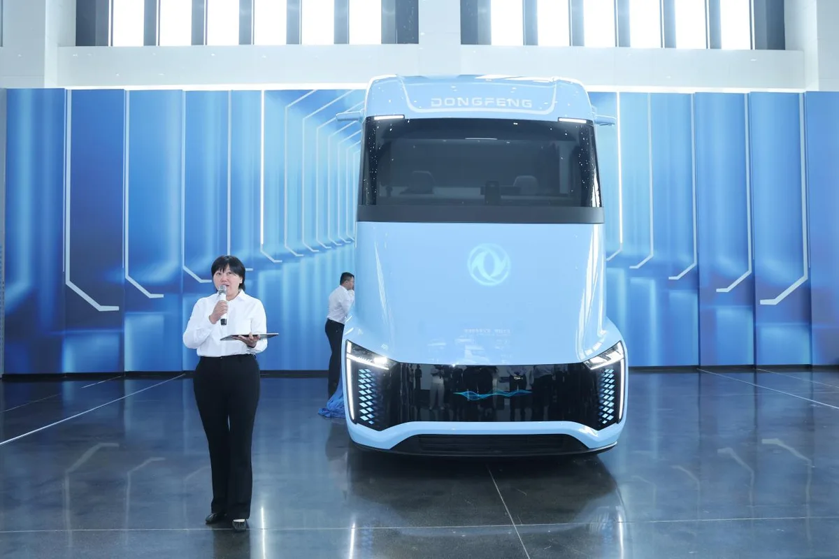 Vista frontal de un camión conceptual Dongfeng azul claro, con una presentadora a su izquierda durante una exhibición.