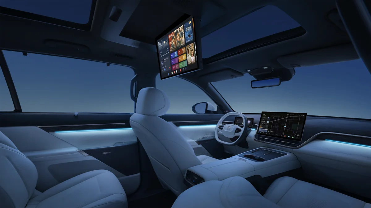 Interior del Dongfeng eπ 008 con pantalla central de navegación, monitor multimedia desplegado en el techo y asientos claros iluminados en azul.