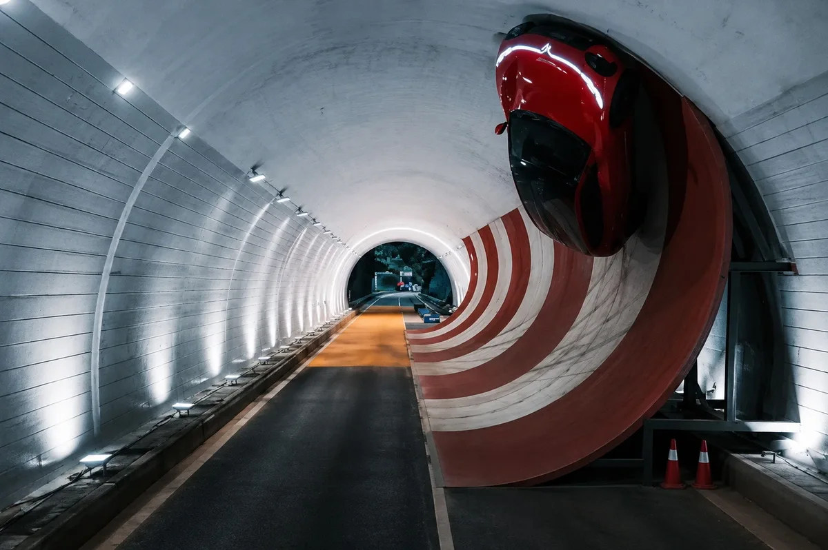 Voyah Passion S rojo circulando boca abajo por la parte superior de un túnel de pruebas, sobre una rampa curva roja y blanca.