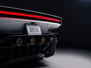 Primer plano de la parte trasera de un Tesla Roadster blanco, con luz roja horizontal, matrícula RDSTR y varios conductos circulares en el difusor inferior.