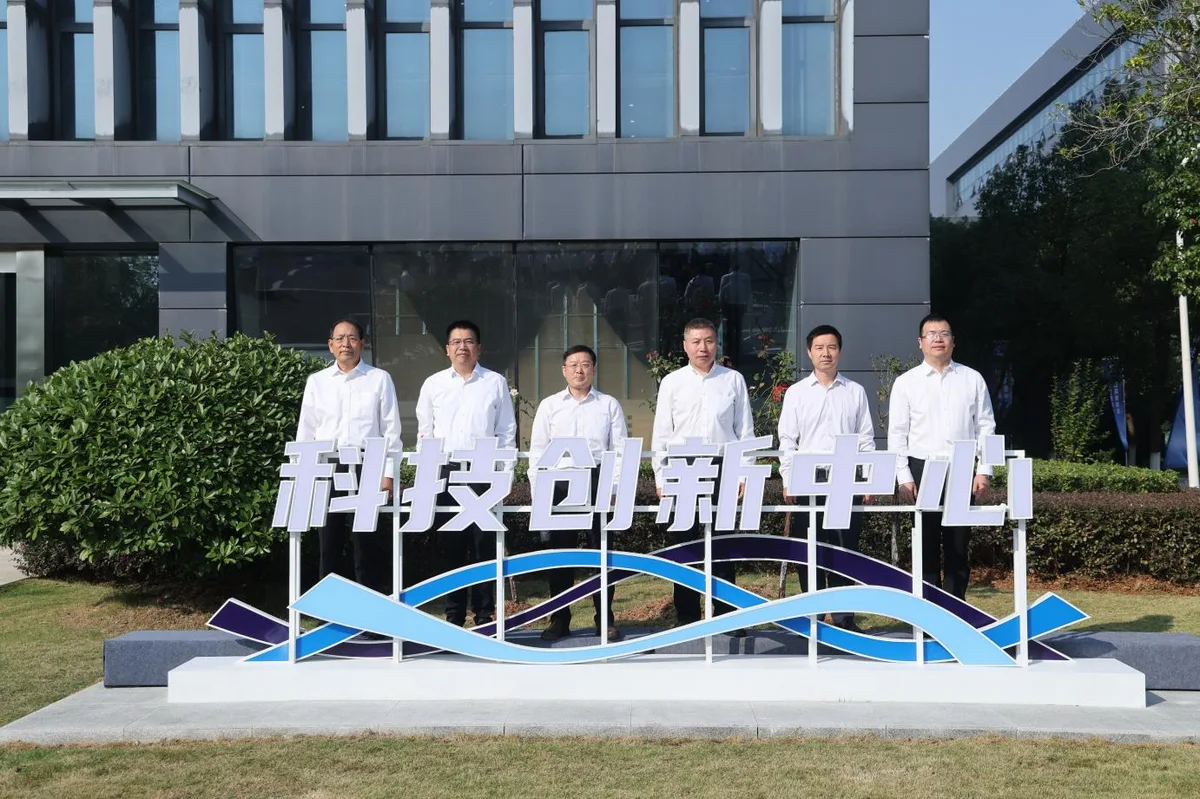 Seis personas posan frente al letrero del Centro de Innovación Científica y Tecnológica de Dongfeng, delante de un edificio moderno en Wuhan, China.
